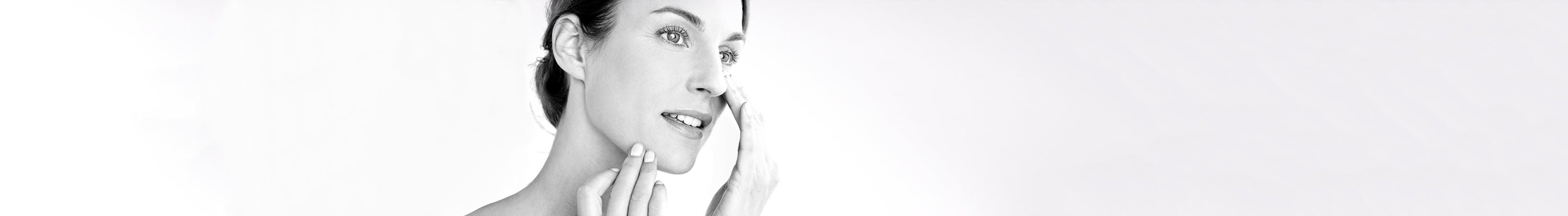 Woman applying cream on her cheek.